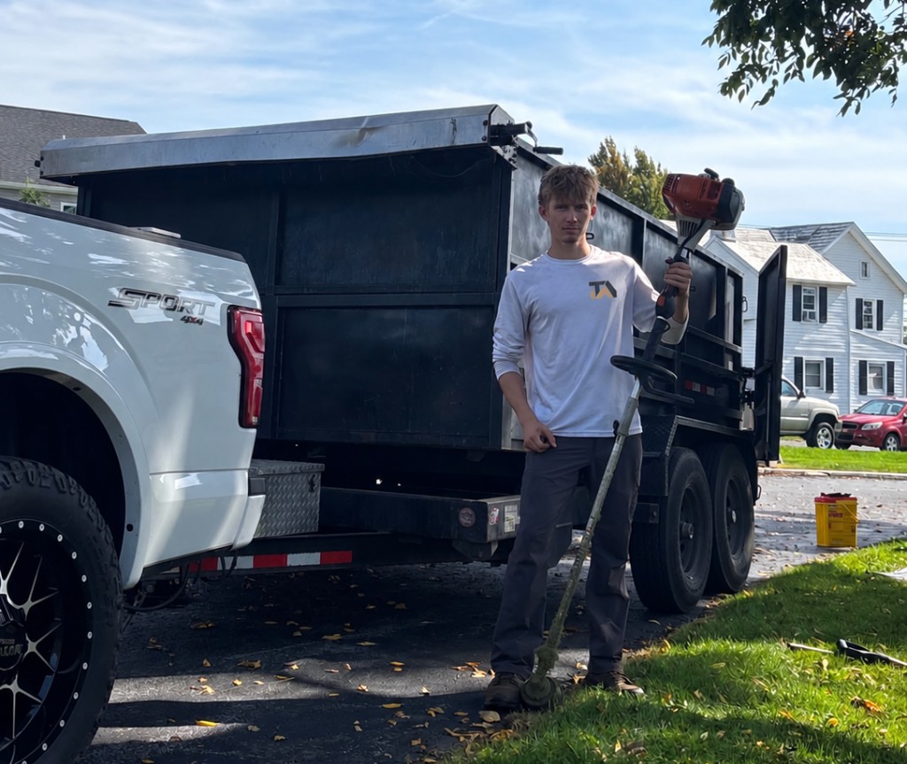 Andrei, owner of Trava Landscaping, beside the company truck with a string trimmer