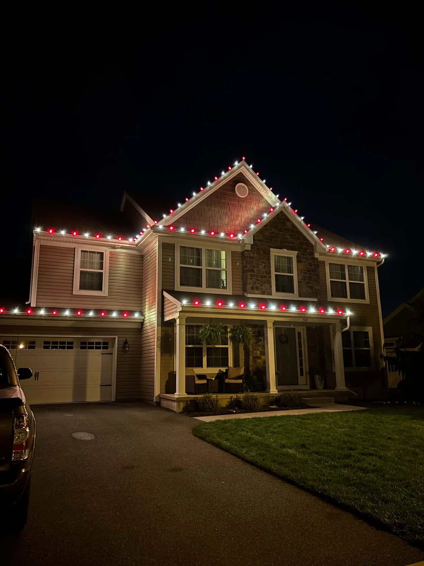 Red and white Christmas lights tracing the rooflines of a two-story home at night